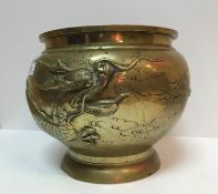 A late 19th Century Chinese brass jardiniere decorated in relief with three toed dragon bearing