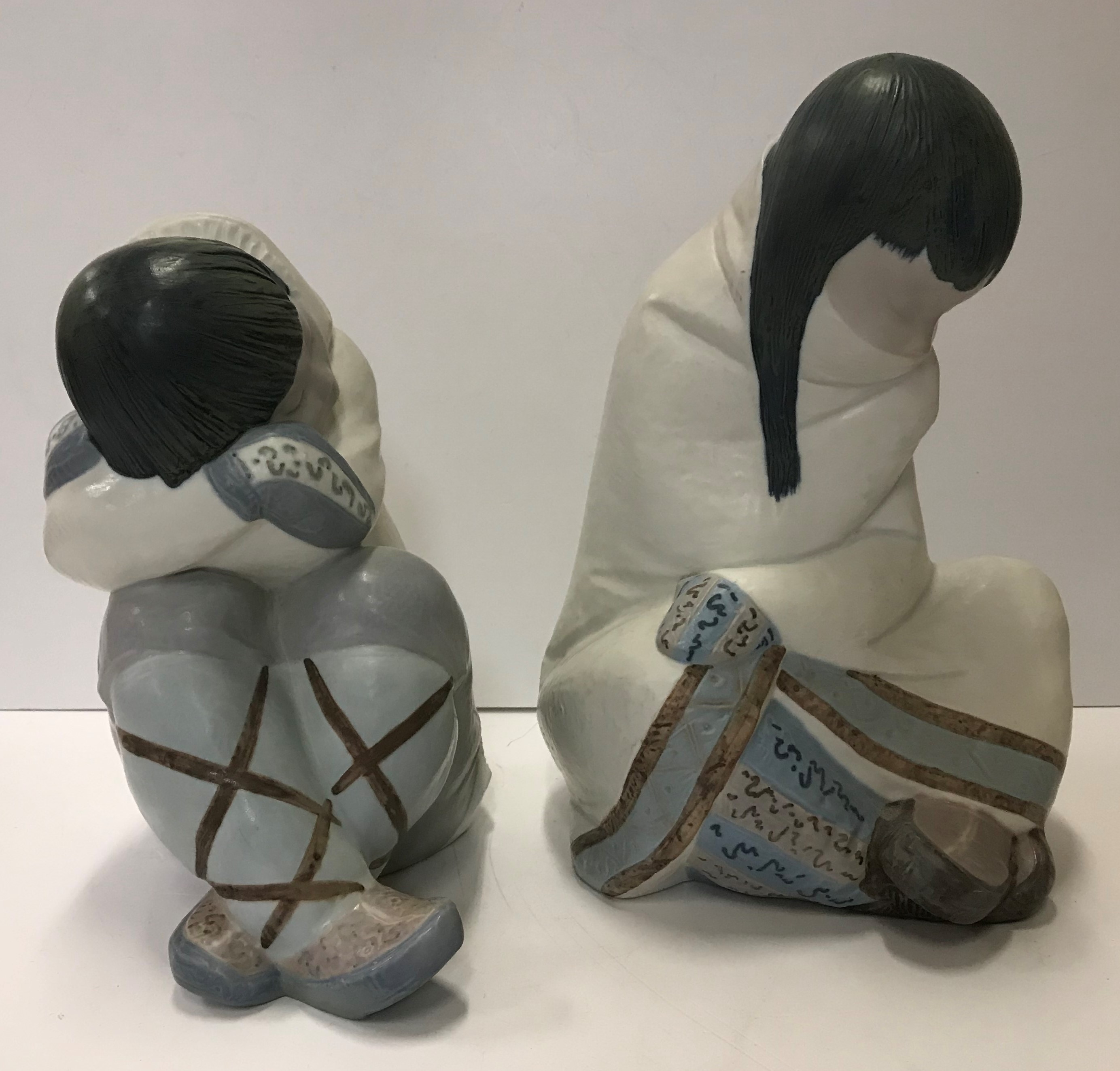 Two Lladro figures of "Seated children", one with crossed legs and head resting upon arms,
