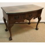 An early 20th Century walnut bow fronted three drawer side table in the Georgian taste,