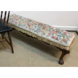 An early 20th Century walnut framed long stool with tapestry seat on acanthus carved cabriole legs