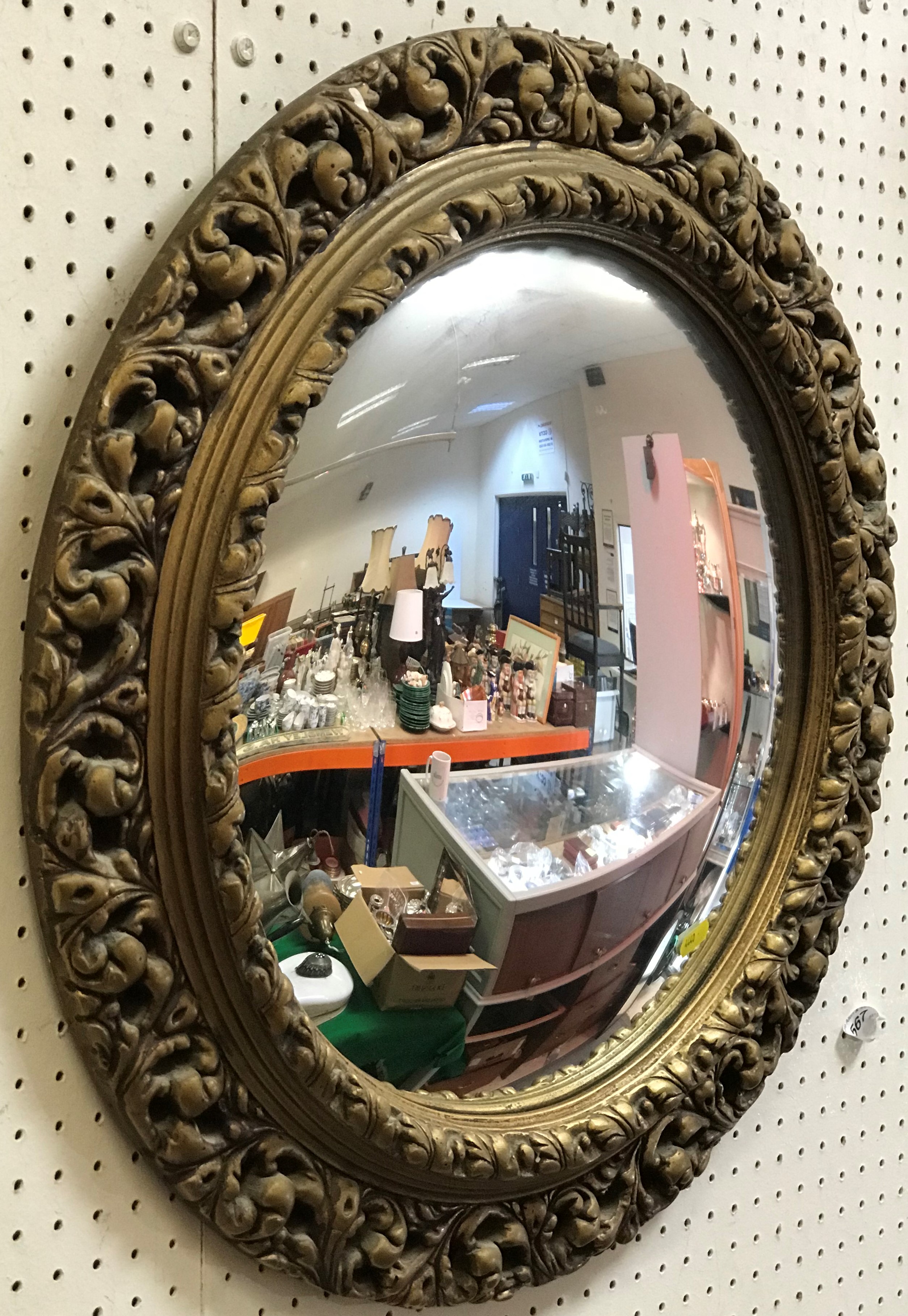 A circular gilt framed wall mirror with convex glass in the Rococo taste,