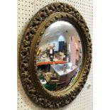 A circular gilt framed wall mirror with convex glass in the Rococo taste,