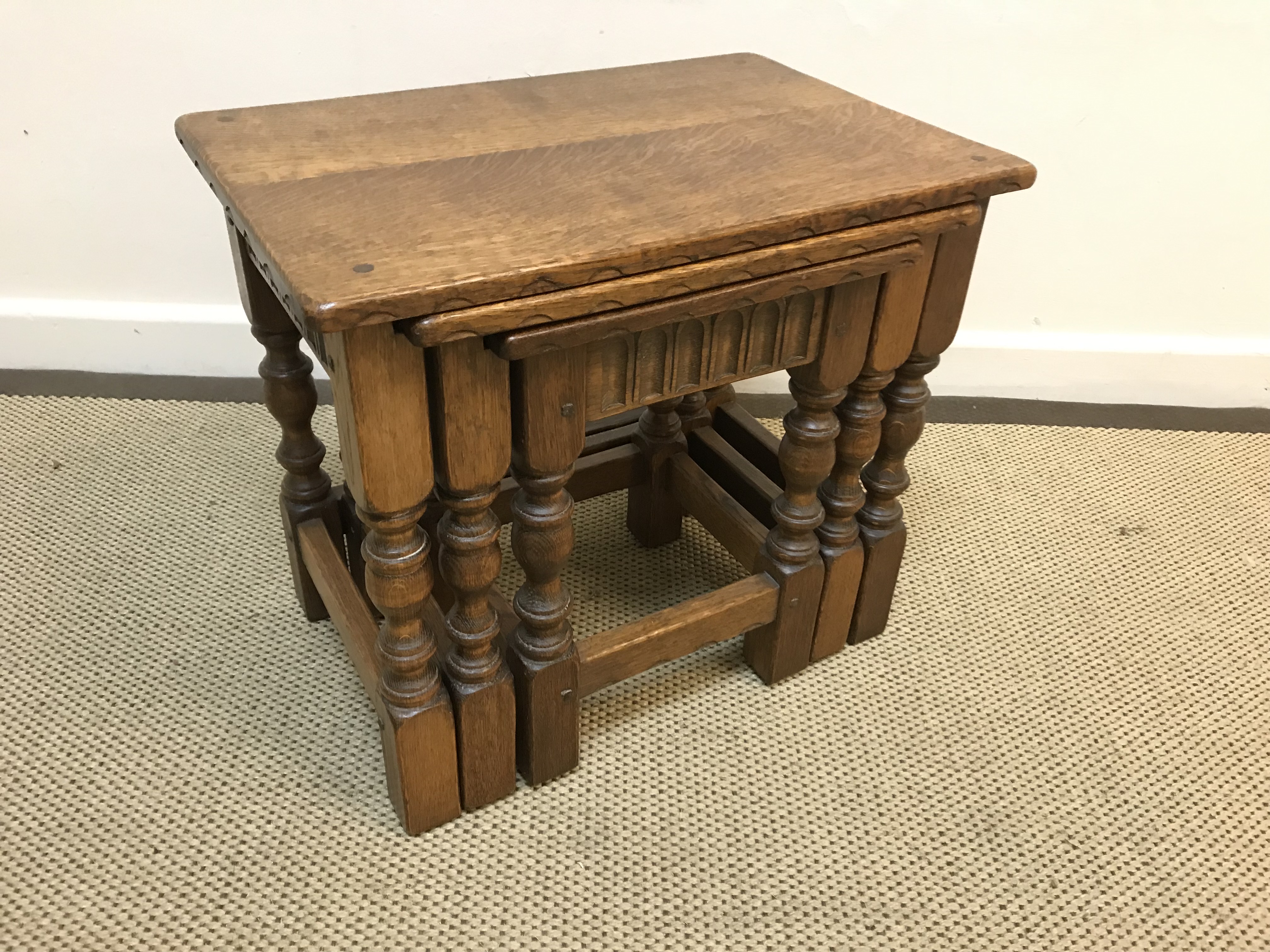 An oak nest of three occasional tables on turned supports to block feet united by stretchers,