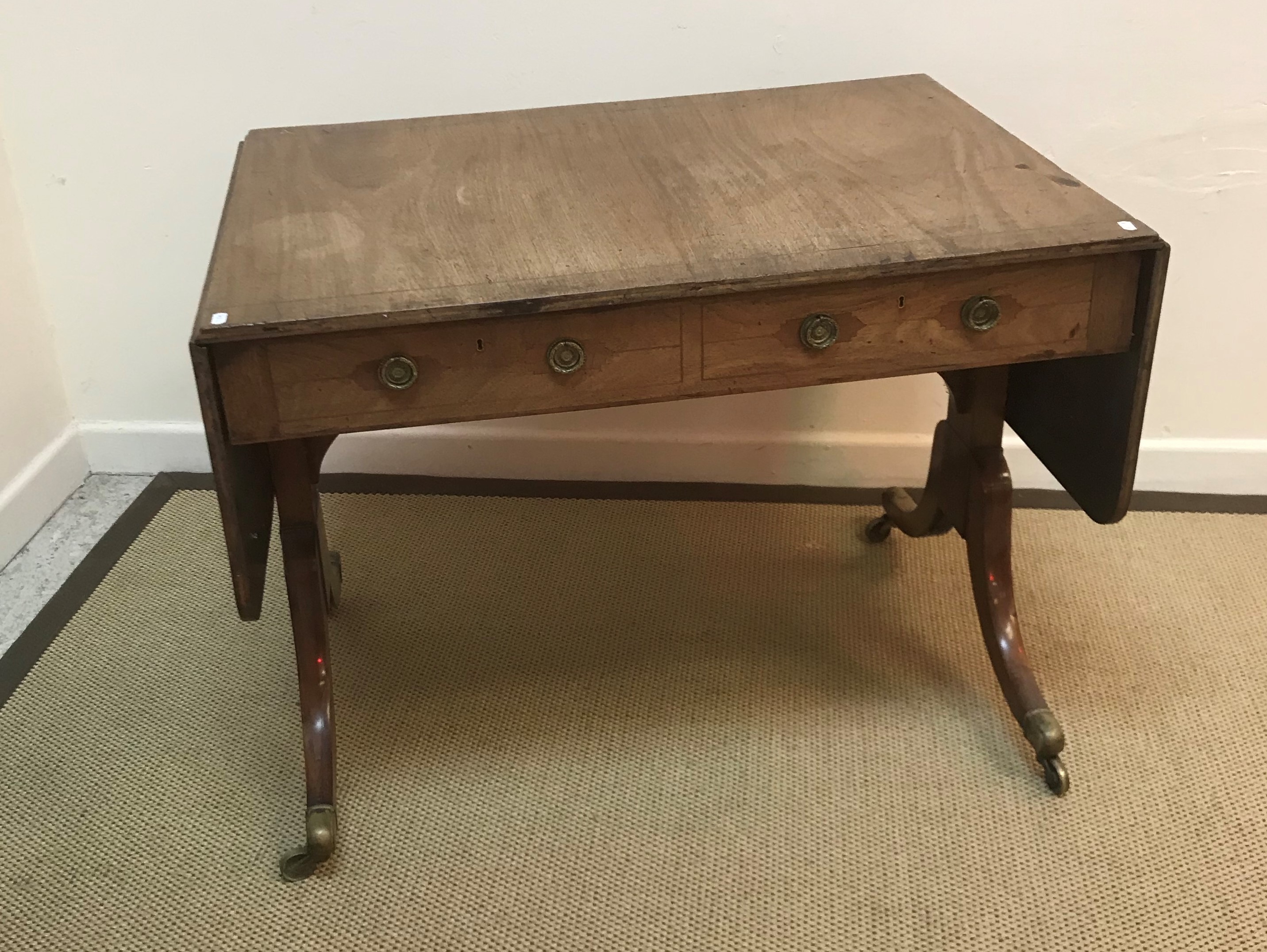 An early 19th Century mahogany and inlaid sofa table with rounded rectangular drop leaves over two