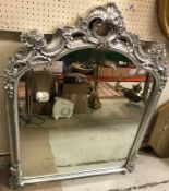 A modern silvered framed mantel mirror in the Rococo taste with scrolling foliate and floral
