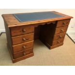 A modern pine writing desk, the plain top with leather insert above two banks of four drawers,