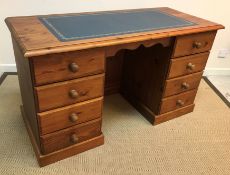 A modern pine writing desk, the plain top with leather insert above two banks of four drawers,