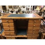 A modern pine writing desk, the plain top with leather insert above two banks of four drawers,