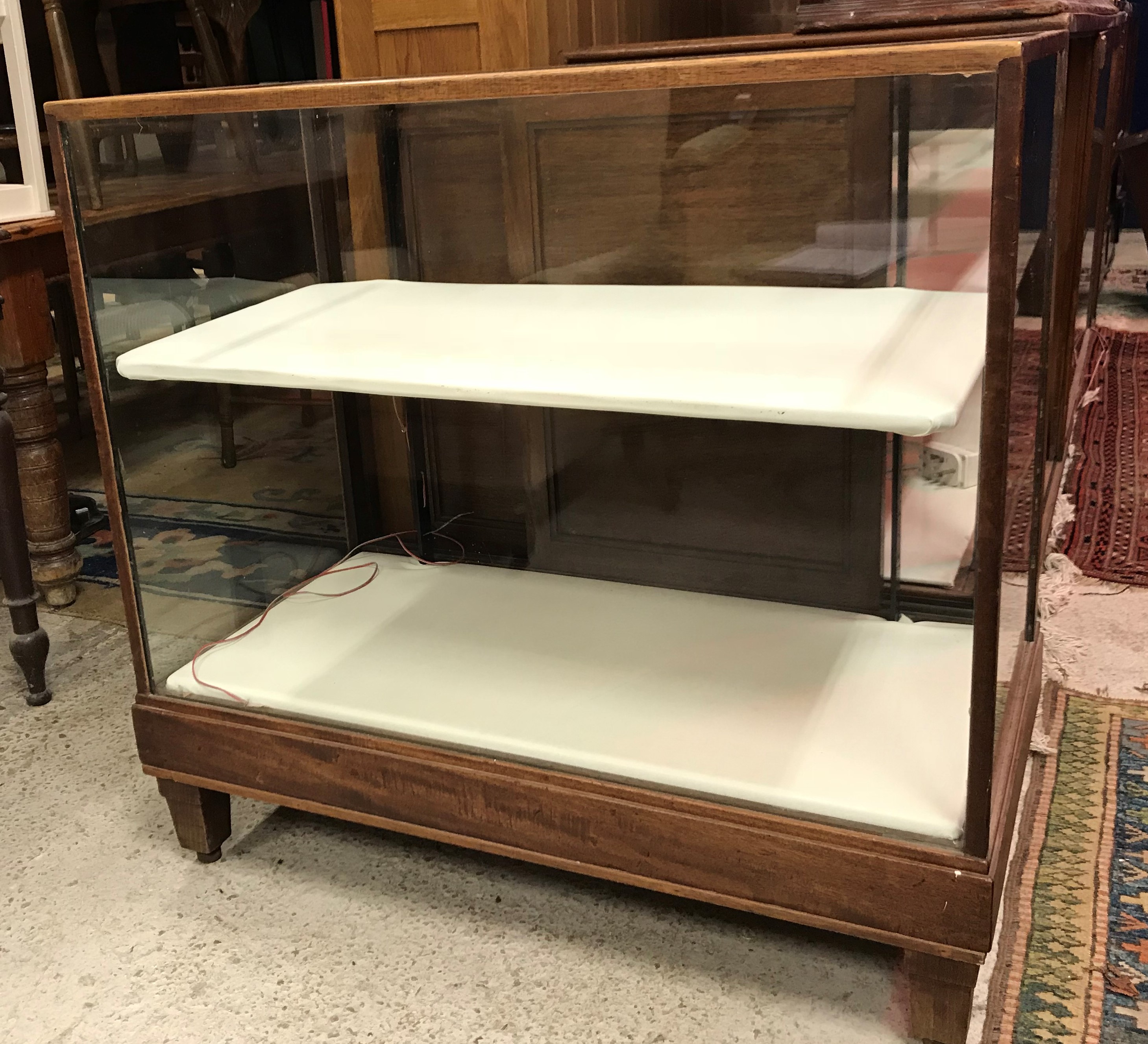 An early 20th Century mahogany framed shop display counter with glazed panels and sliding door to