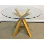 A modern circular breakfast table with glass top on a stained beech quadruped base, 109.