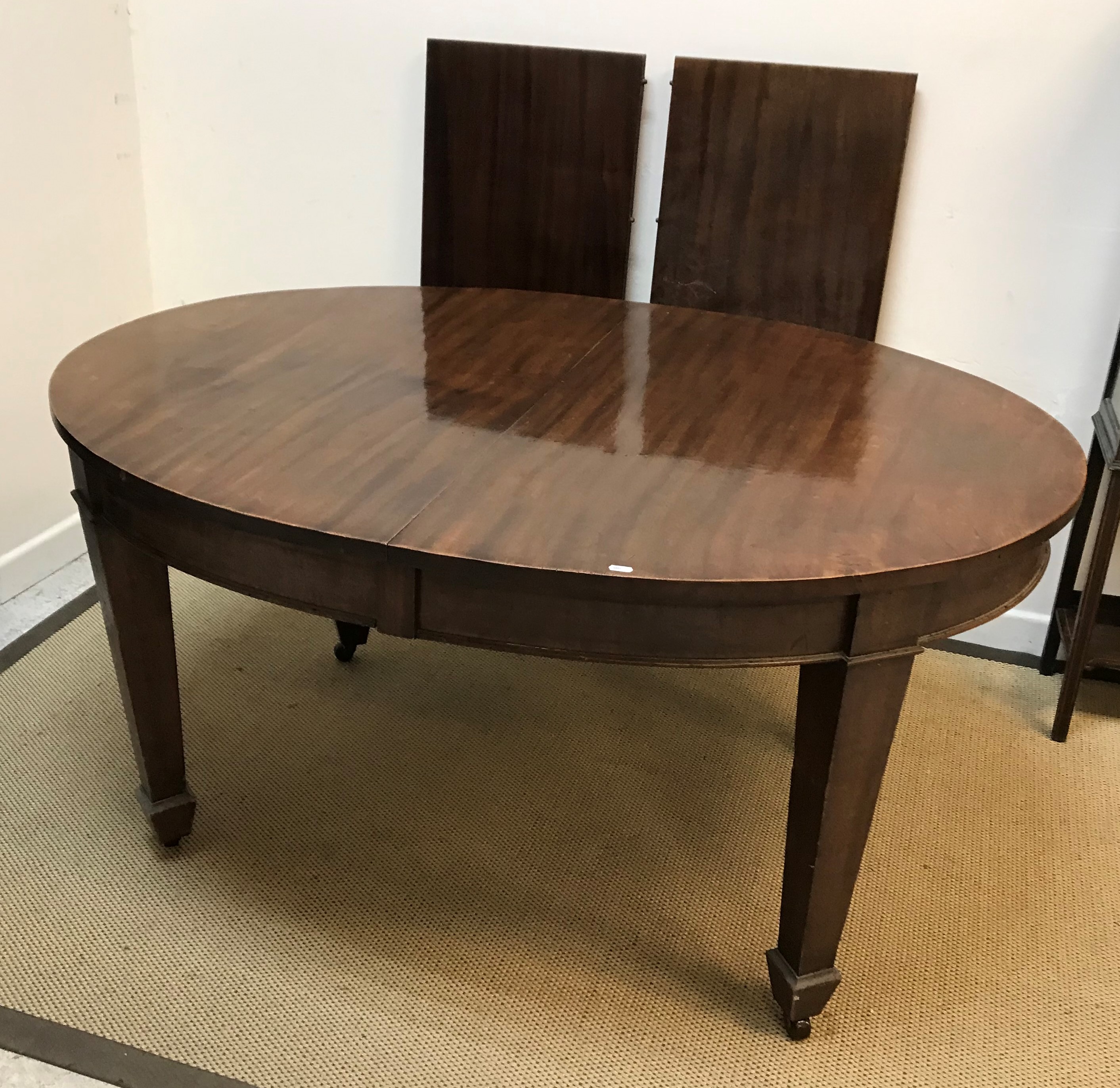 An Edwardian mahogany D end dining table on square tapered legs to spade feet (one extra leaf),