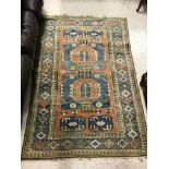 A Caucasian rug, the central panel set with geometric design on a salmon pink ground, within a blue,