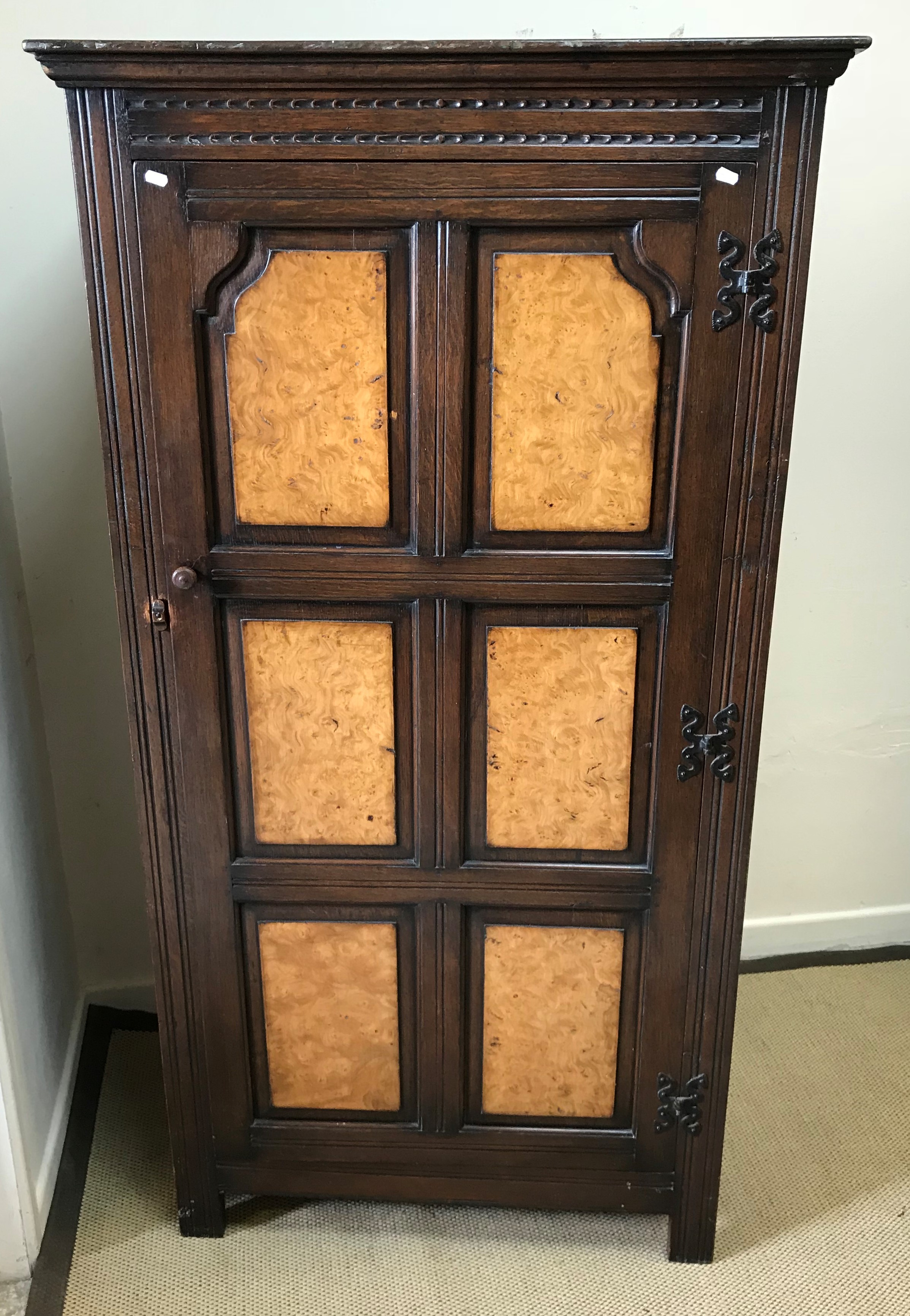 A mid 20th Century oak hall cupboard, the door with six burr walnut veneered fielded panels,