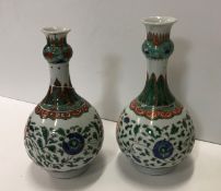 A matched pair of Chinese Kangxi famille verte onion-shaped vases with all-over scrolling floral