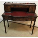 A reproduction mahogany lady's writing table with raised superstructure of drawers and cupboard