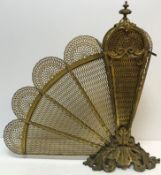 A Victorian pierced brass fan fire screen in the Rococo taste with scrolling acanthus handle /