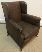 A circa 1900 buttoned leather upholstered wing back scroll arm child's chair on square tapered legs