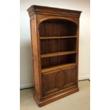 A Wesley Barrell cherry wood bookcase cabinet with moulded cornice over three open shelves and two