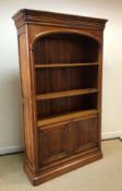 A Wesley Barrell cherry wood bookcase cabinet with moulded cornice over three open shelves and two