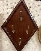 A set of four brass hat and coat hooks mounted on a mahogany lozenge panel with moulded edge,