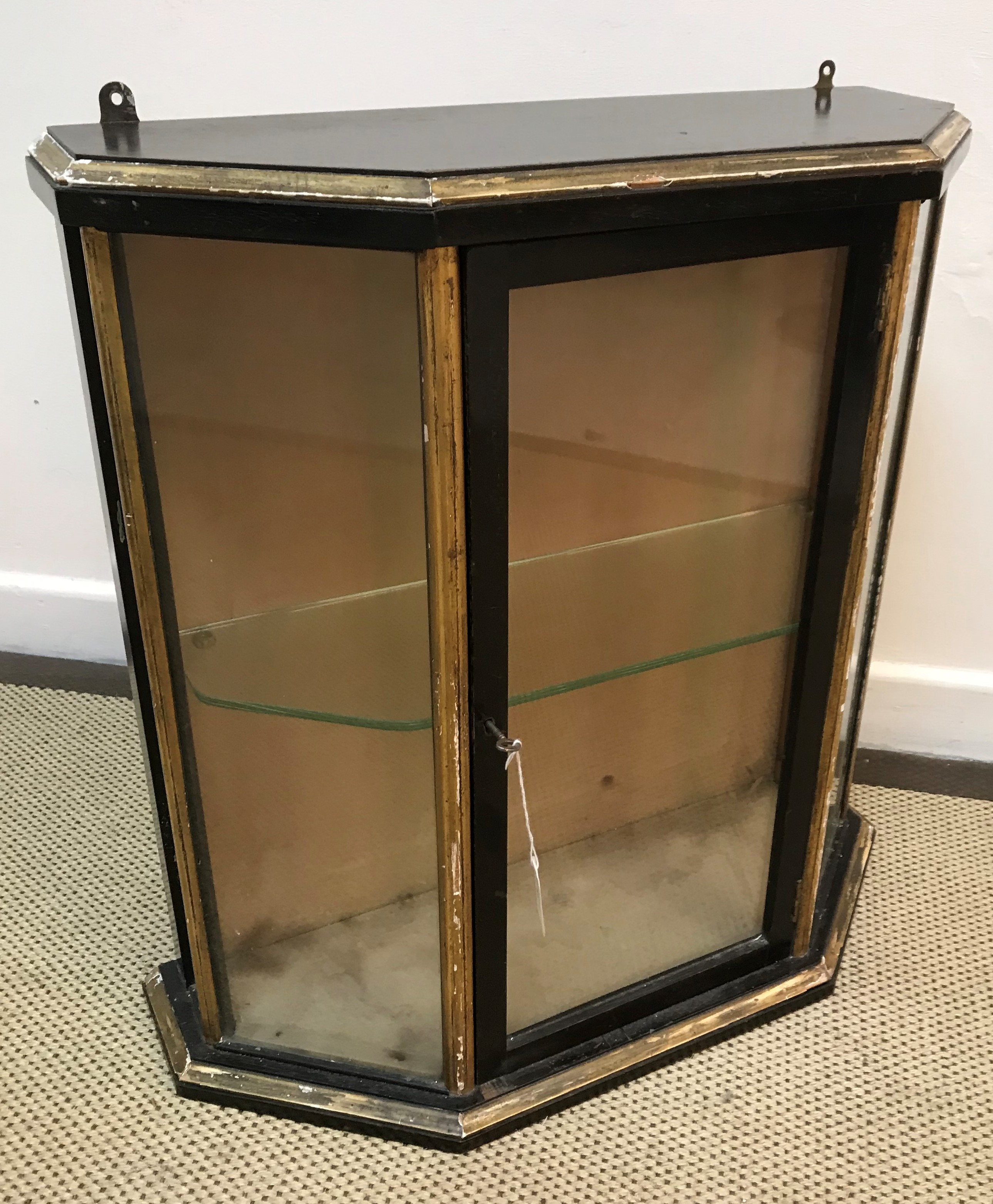 An early 20th Century ebonised and gilt decorated five sided wall hanging display cabinet,