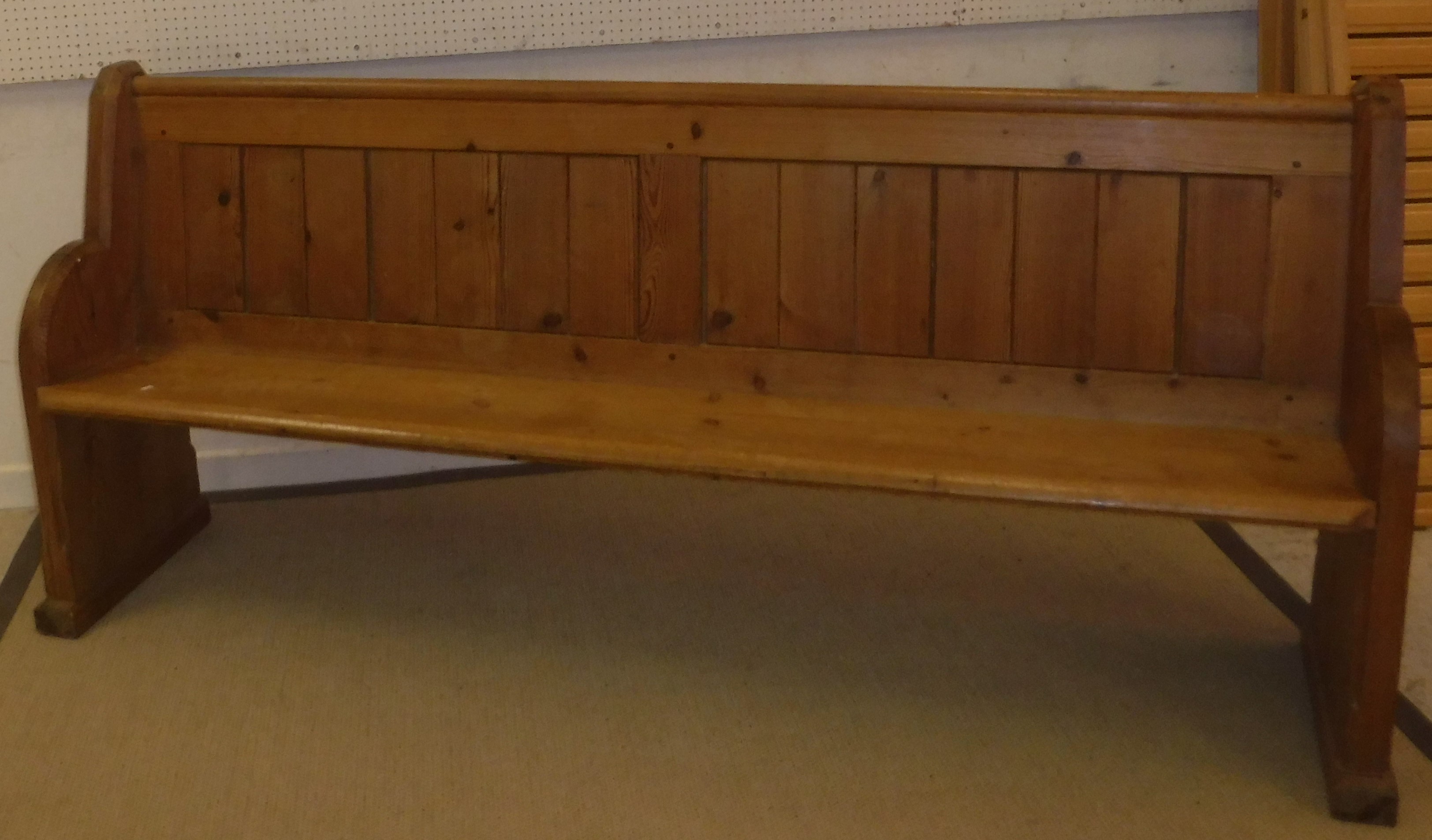 A circa 1900 pitch pine chapel pew of plain form on plank end supports,