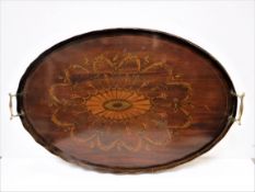 An Edwardian mahogany and inlaid and penwork decorated oval drinks' tray with two brass handles,