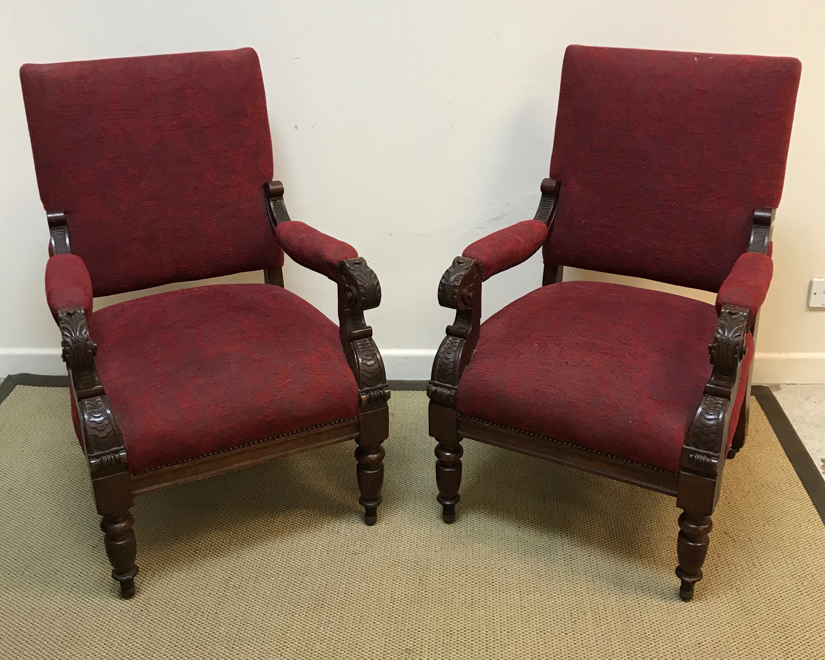 A pair of Victorian carved walnut framed open arm chairs with upholstered back panels and seats,