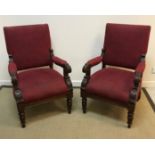 A pair of Victorian carved walnut framed open arm chairs with upholstered back panels and seats,