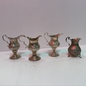 A collection of three various Georgian silver cream jugs with embossed floral decoration each