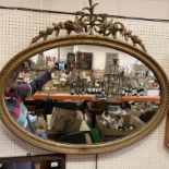 A circa 1900 gilt framed oval wall mirror with foliate and floral decorated surmount over an egg