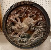 A Chinese carved painted and gilded wooden roundel depicting a running rabbit amongst foliage,
