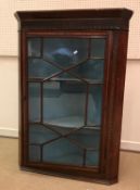 A late George III mahogany and inlaid hanging corner cupboard with astragal glazed door enclosing