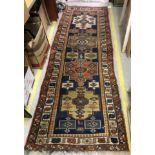 A Caucasian runner, the central panel set with repeating medallions ona blue ground,