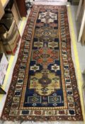 A Caucasian runner, the central panel set with repeating medallions ona blue ground,