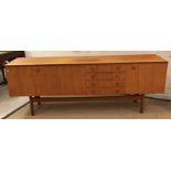 A mid 20th Century teak sideboard with two cupboard doors flanking a fall front cocktail
