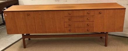 A mid 20th Century teak sideboard with two cupboard doors flanking a fall front cocktail