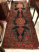 A Caucasian runner, the central panel set with scrolling medallions set on a black and red ground,