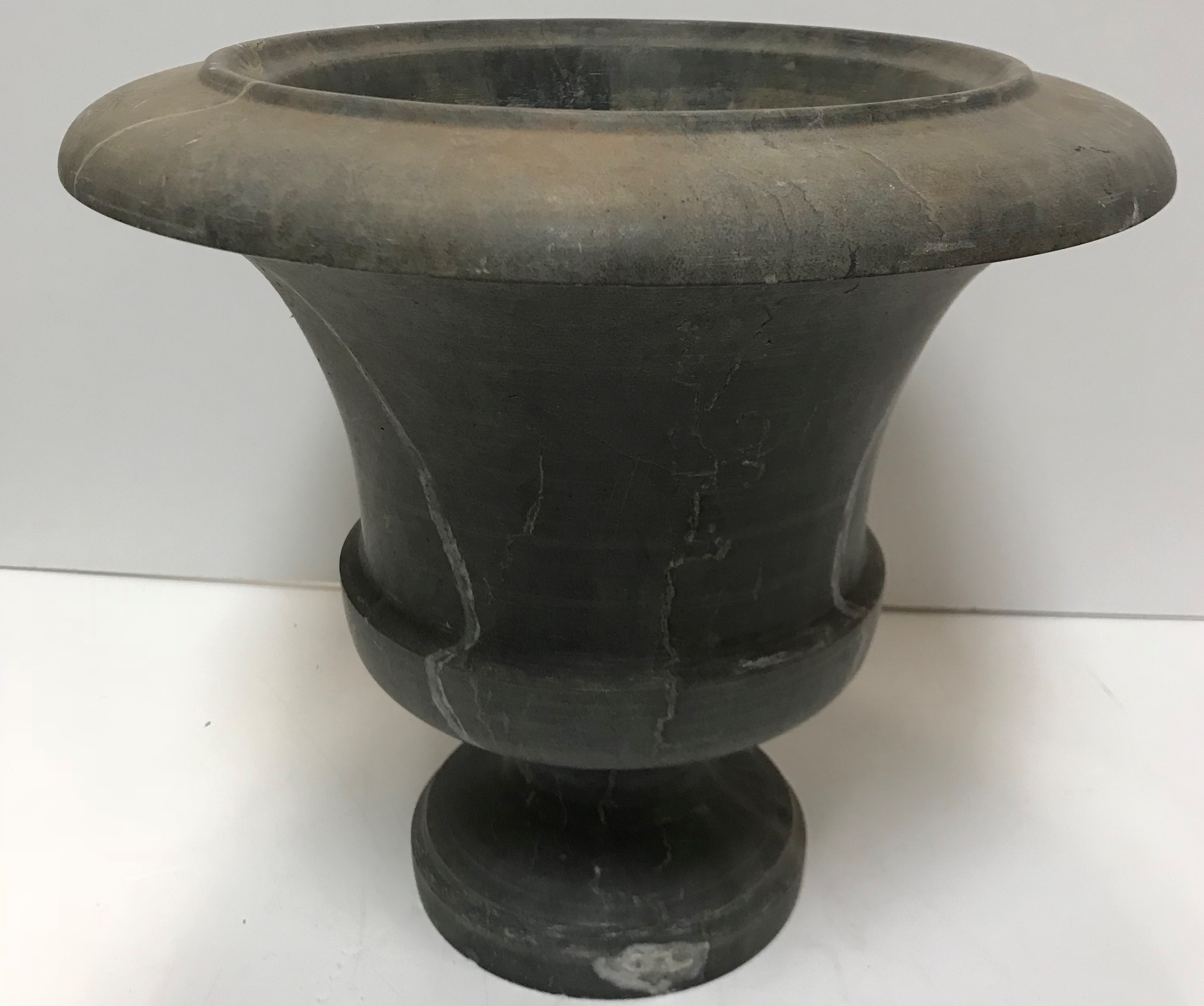 A grey veined dark grey marble urn with flared rim raised on a circular foot 36 cm diameter x 32 cm