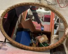 A pair of circa 1900 giltwood and gesso framed oval wall mirrors with foliate and berry decoration,