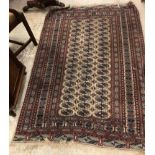 A Bokhara rug, the central panel set with repeating elephant foot medallions on a cream ground,