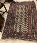 A Bokhara rug, the central panel set with repeating elephant foot medallions on a cream ground,