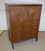 A walnut cabinet with two doors over three drawers on square supports by Waring & Gillow Ltd of