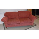 A modern patterned terracotta upholstered scroll arm two seat sofa on turned legs to brass caps and