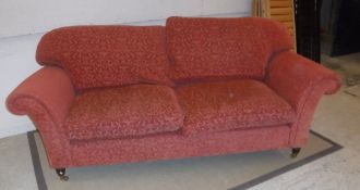 A modern patterned terracotta upholstered scroll arm two seat sofa on turned legs to brass caps and