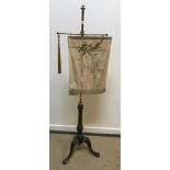 An early 19th Century ebonised, brass and gilt decorated pole screen on tripod base,