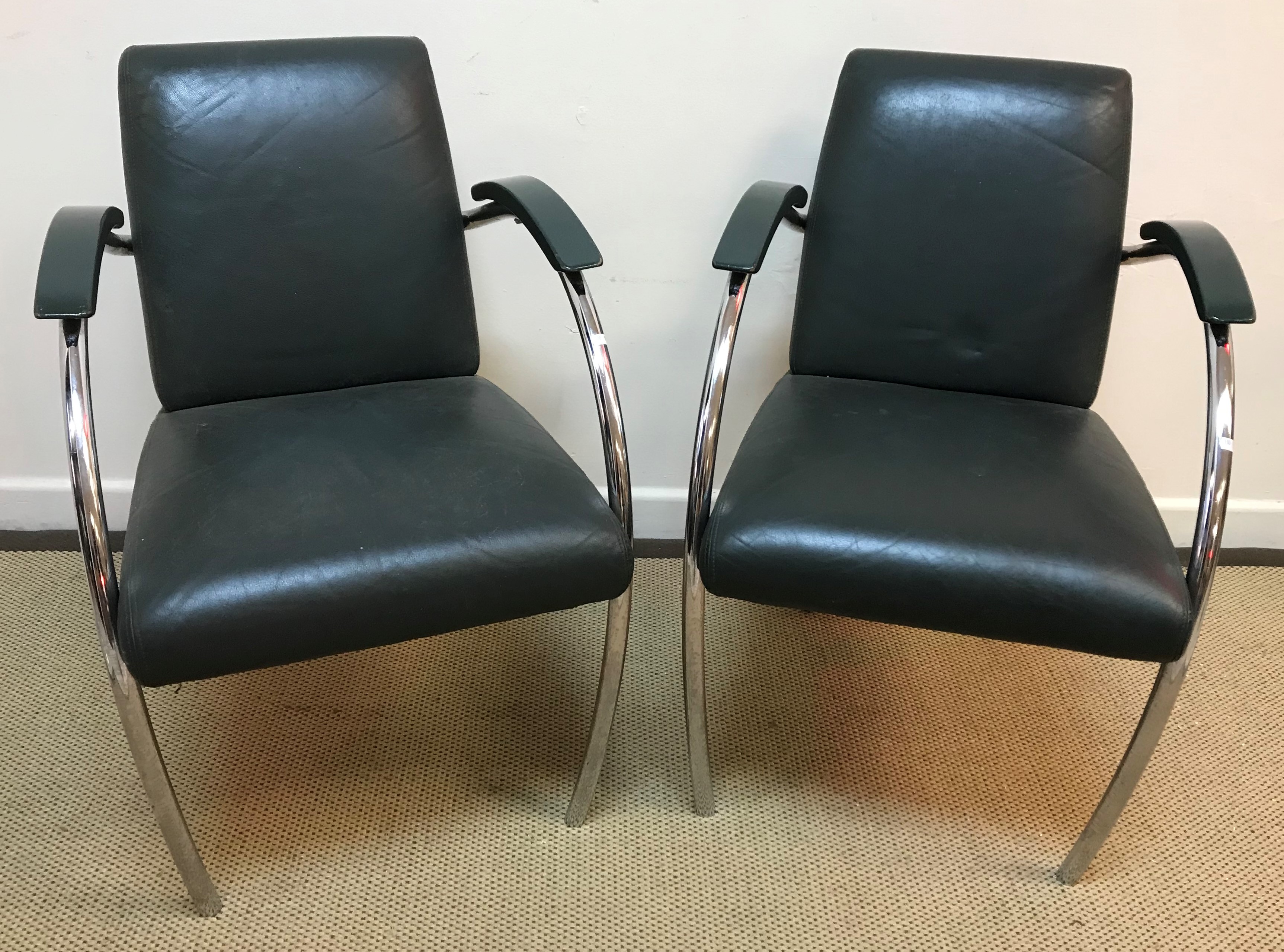 A pair of Art Deco style chrome framed and green leather upholstered elbow chairs with green