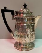 A late Victorian silver embossed hot water jug with ebonised finial and handle,