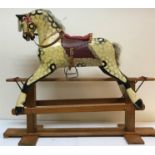 An early 20th Century dapple painted rocking horse with saddle and harness, overall length 143 cm,