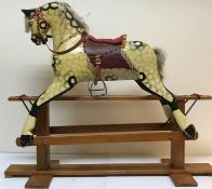 An early 20th Century dapple painted rocking horse with saddle and harness, overall length 143 cm,